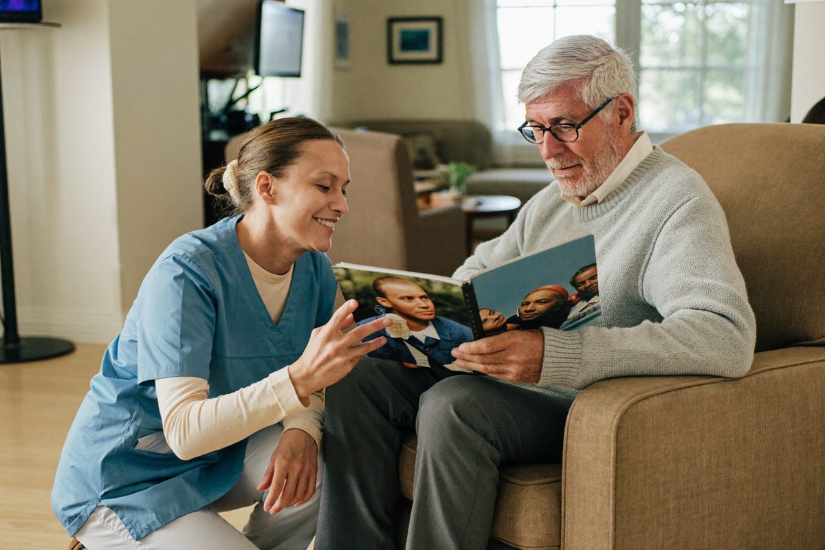 A care worker and an older woman looking through a photo album